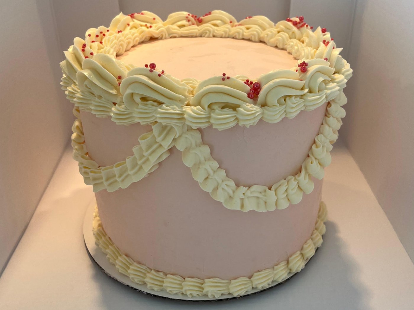 Bento cake rose pâle décoré de crème vintage et de perles rouges